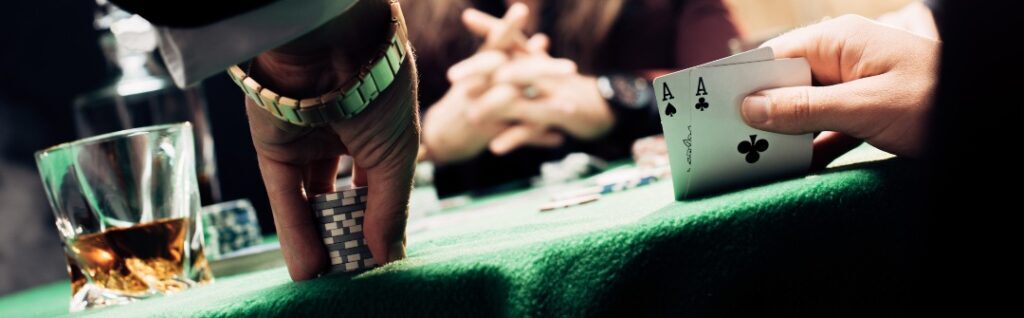 panoramic shot of man touching playing cards and poker chips near player