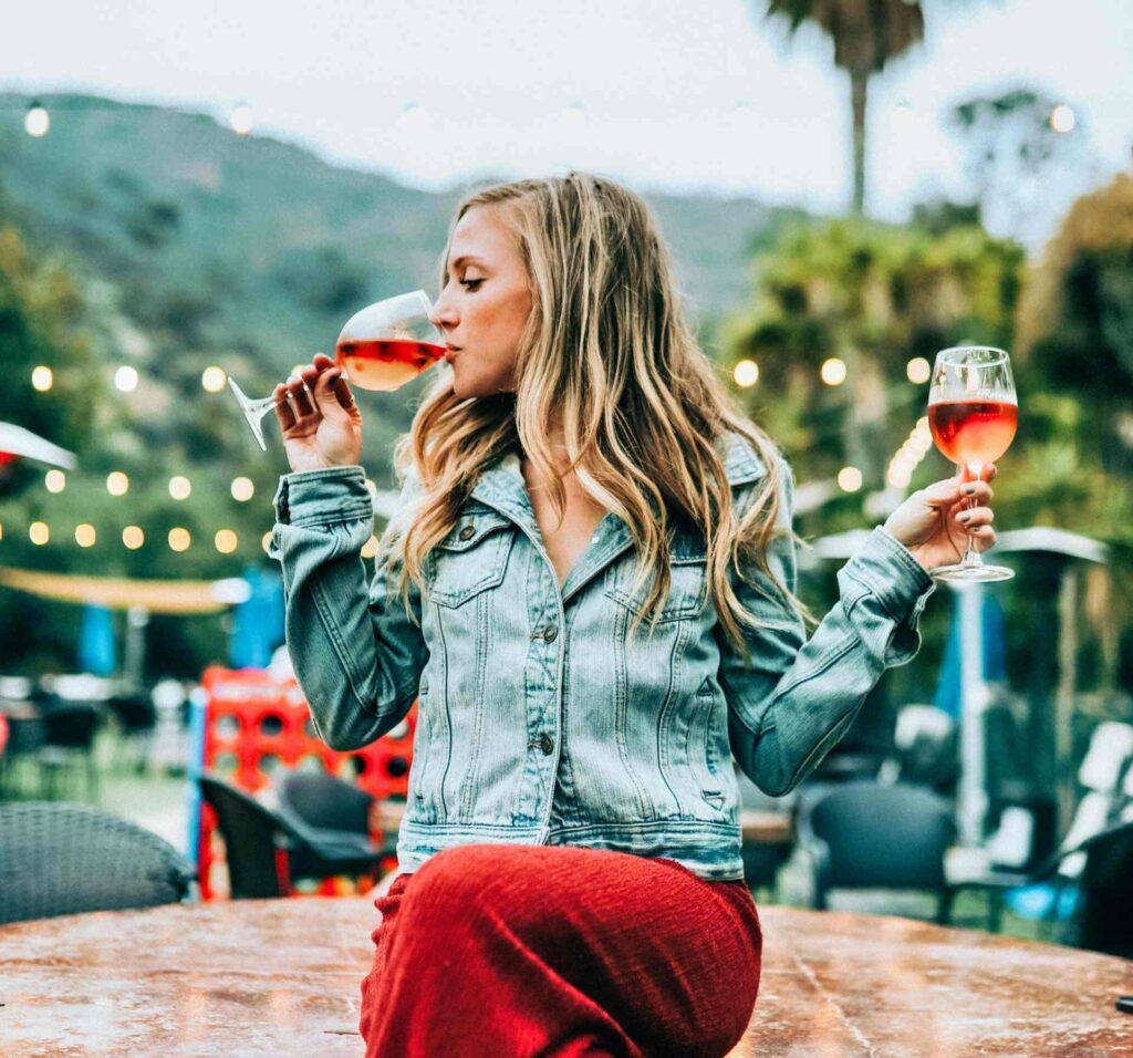 Girl sitting on a table drinking rosé wine from Provence